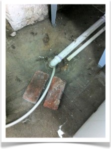 Hose #1 positioned to take water from the downed basement drain. Bricks are there to keep the hose in place via friction.