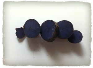 A small, cooked (roasted), purple potato that has been sliced.