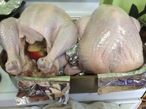 Prepped turkeys ready for roasting. Birds are sitting on, and separated by, Aluminim-foil "snakes".