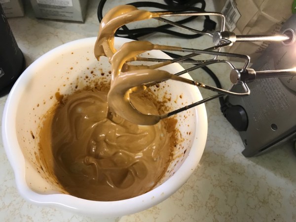 Finished dalgona coffee foam on beaters showing soft peaks